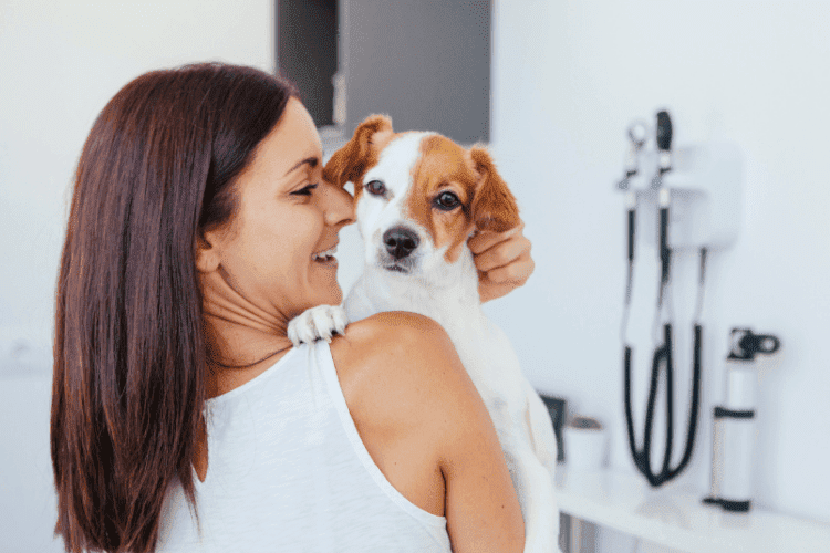 Woman holding her dog during a veterinary visit.